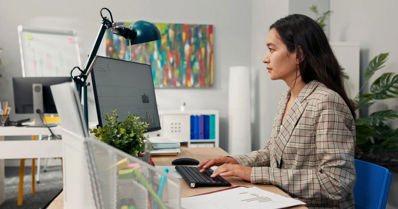 Professional woman actively working at a computer, analyzing data charts on the screen