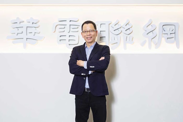 Man in suit stands smiling into camera